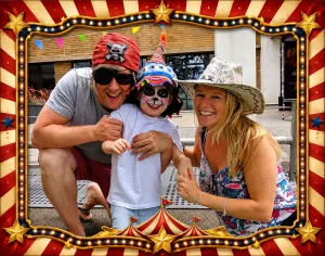 Child with pirate-inspired face painting smiling with family at a children's event in Bristol.