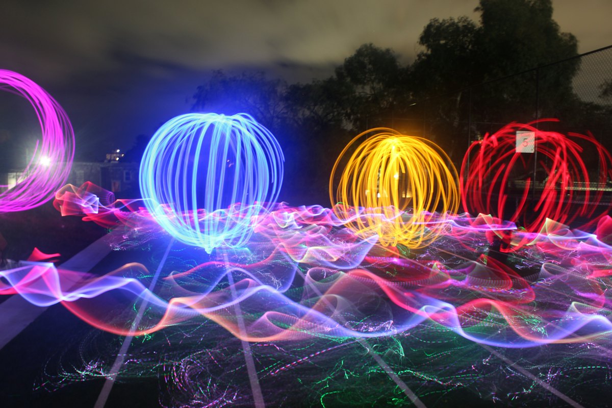 Blue, yellow and red glowing light orbs and neon light trails at night