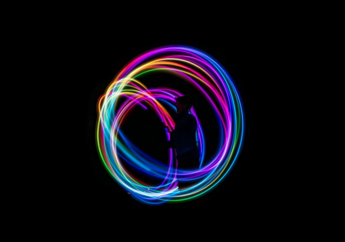 Rainbow light trails from spinning glow poi in the dark